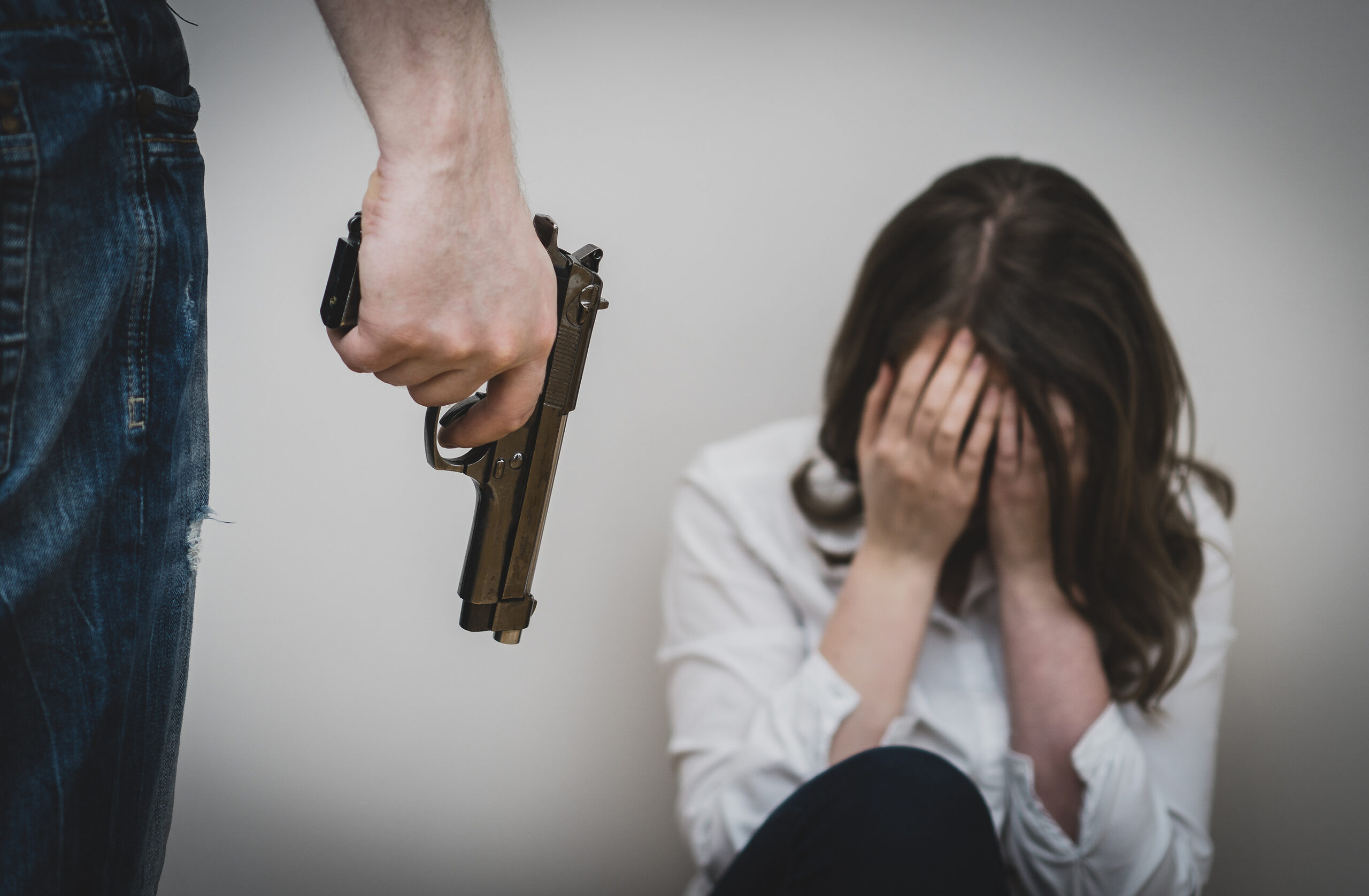 Home violence concept. Man with gun threaten woman.