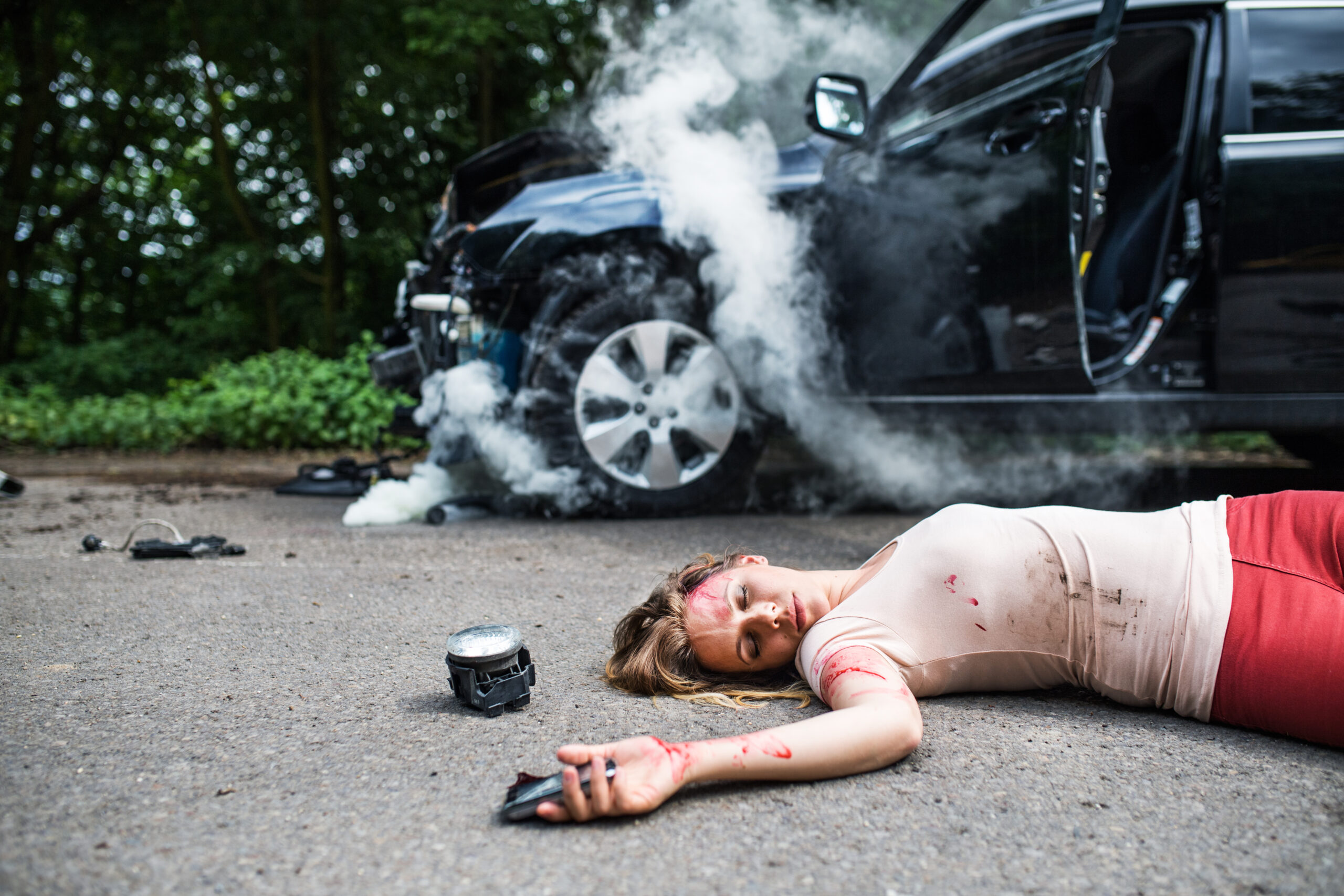 Young injured woman lying on the road after a car accident, unconscious.